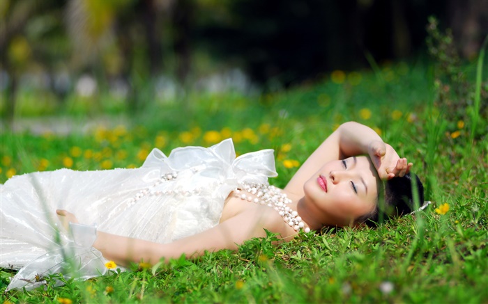 亞洲白色連衣裙的女孩躺在草地上 桌布 圖片