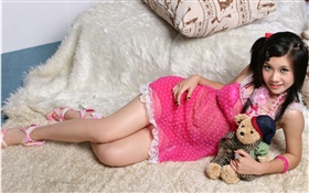 微笑粉紅色連衣裙的亞洲女孩，床，玩具
