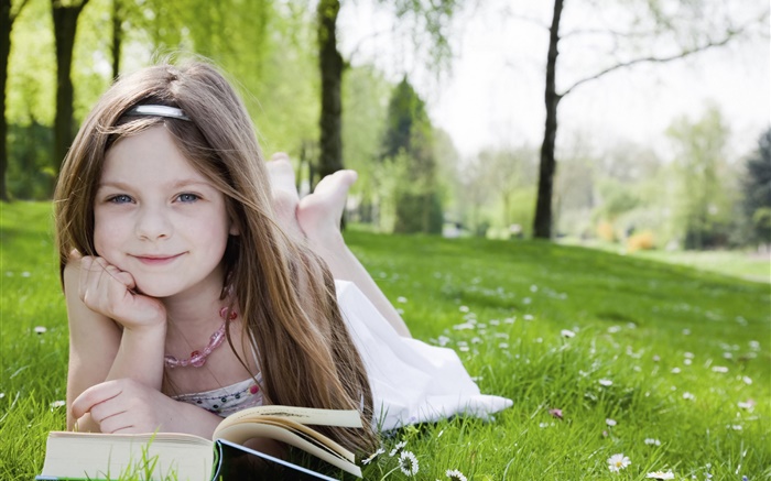 可愛的小女孩在草地上，看書 桌布 圖片