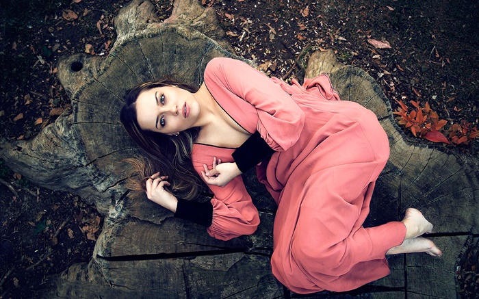 粉紅色連衣裙的女孩躺在樹樁 桌布 圖片